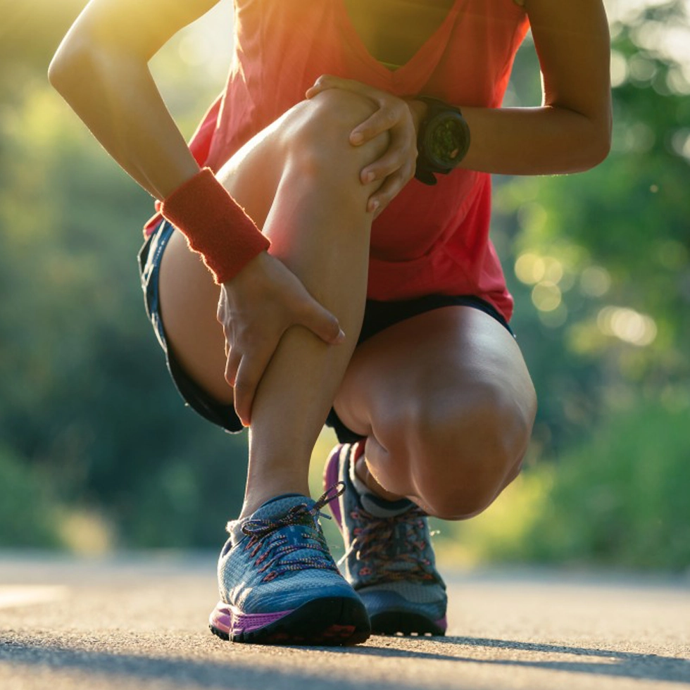 Photobiomodulation Therapy for Knee Pain – BionwoRx Carmel IN Woman holding her knee in pain before receiving Photobiomodulation Therapy (PBMT) at BionwoRx Center for Functional and Regenerative Medicine in Carmel, Indiana, for inflammation and joint recovery.