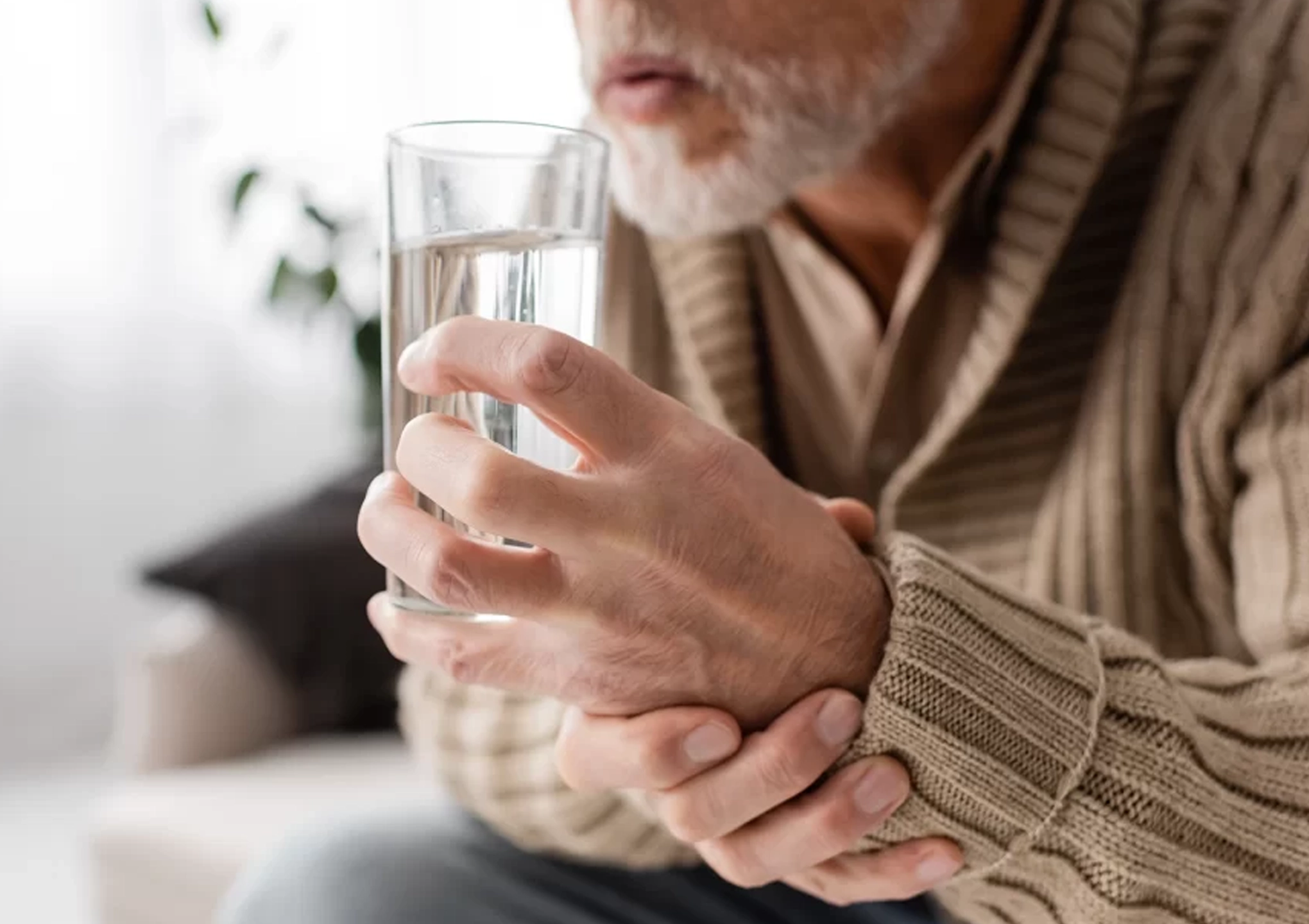 Elderly man with Parkinson’s Disease holding a glass of water, symbolizing daily living challenges and supportive care at BionwoRx: Center for Functional and Regenerative Medicine in Carmel, Indiana