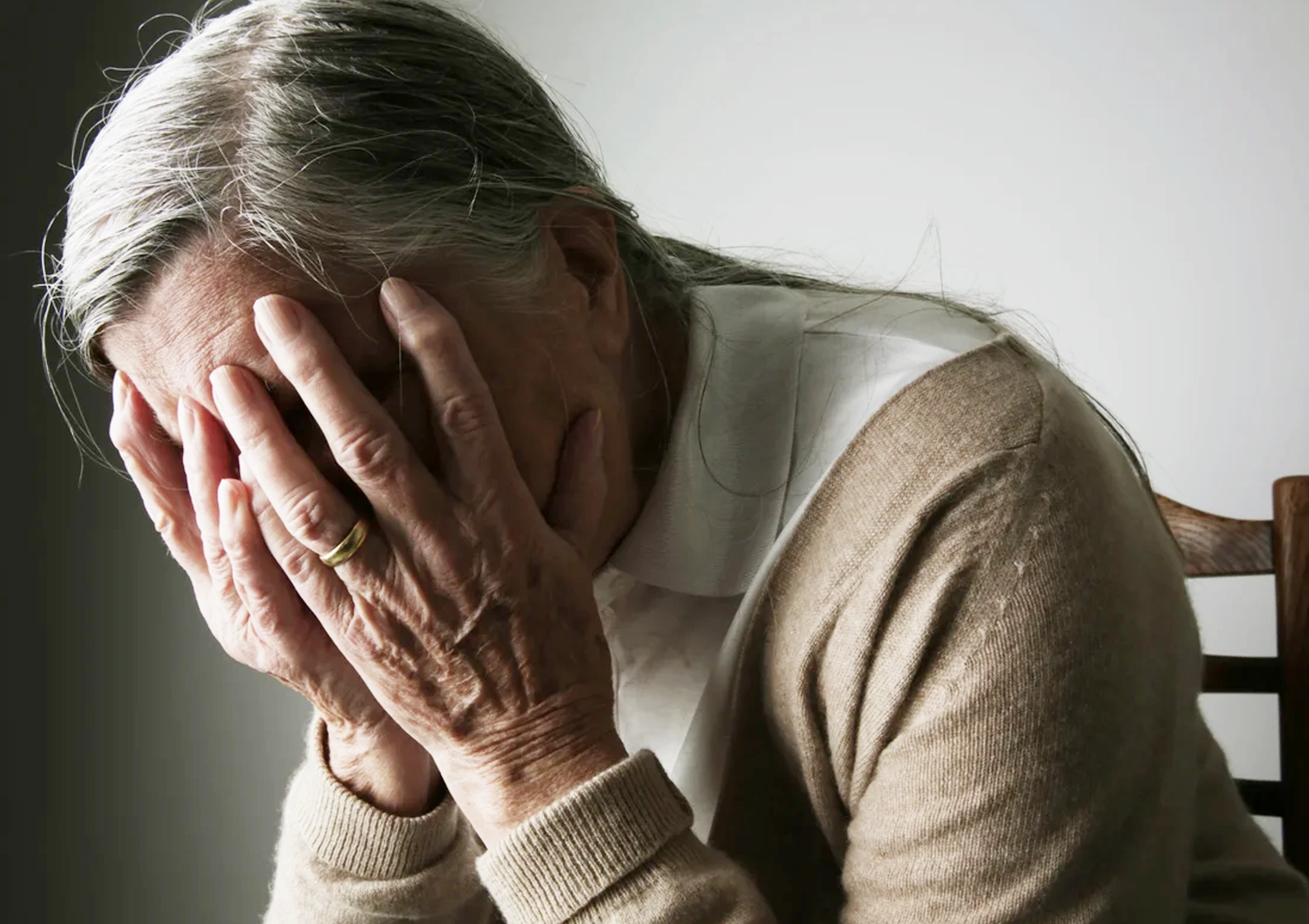 Older woman with Alzheimer’s disease holding her head, representing cognitive strain and neurological challenges addressed with supportive therapies at BionwoRx in Carmel, Indiana
